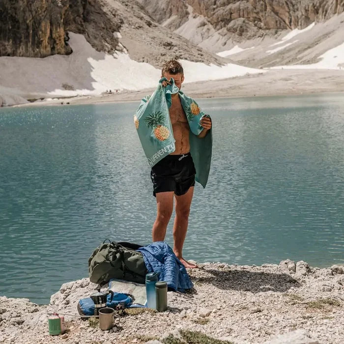 Lifestyle image of a man drying himelf with a Lifeventure printed soft fibre travel towel whilst at the beach