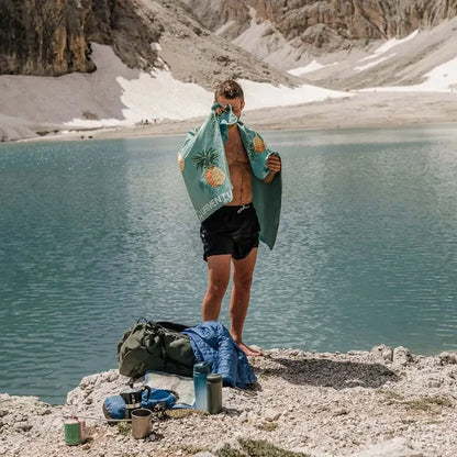 Lifestyle image of a man drying himelf with a Lifeventure printed soft fibre travel towel whilst at the beach
